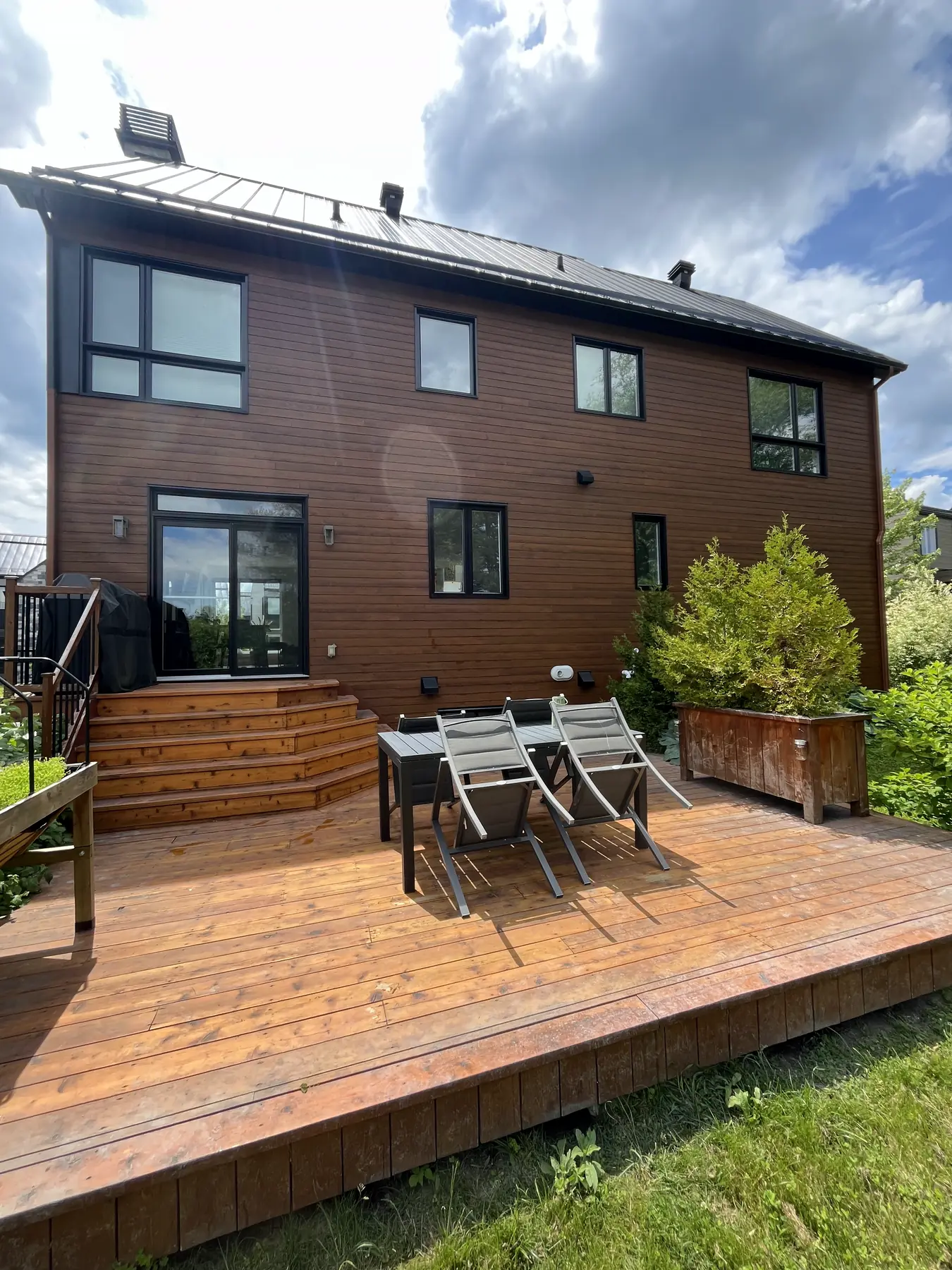 Grande terrasse en bois fraîchement lavée derrière une maison à revêtement de bois